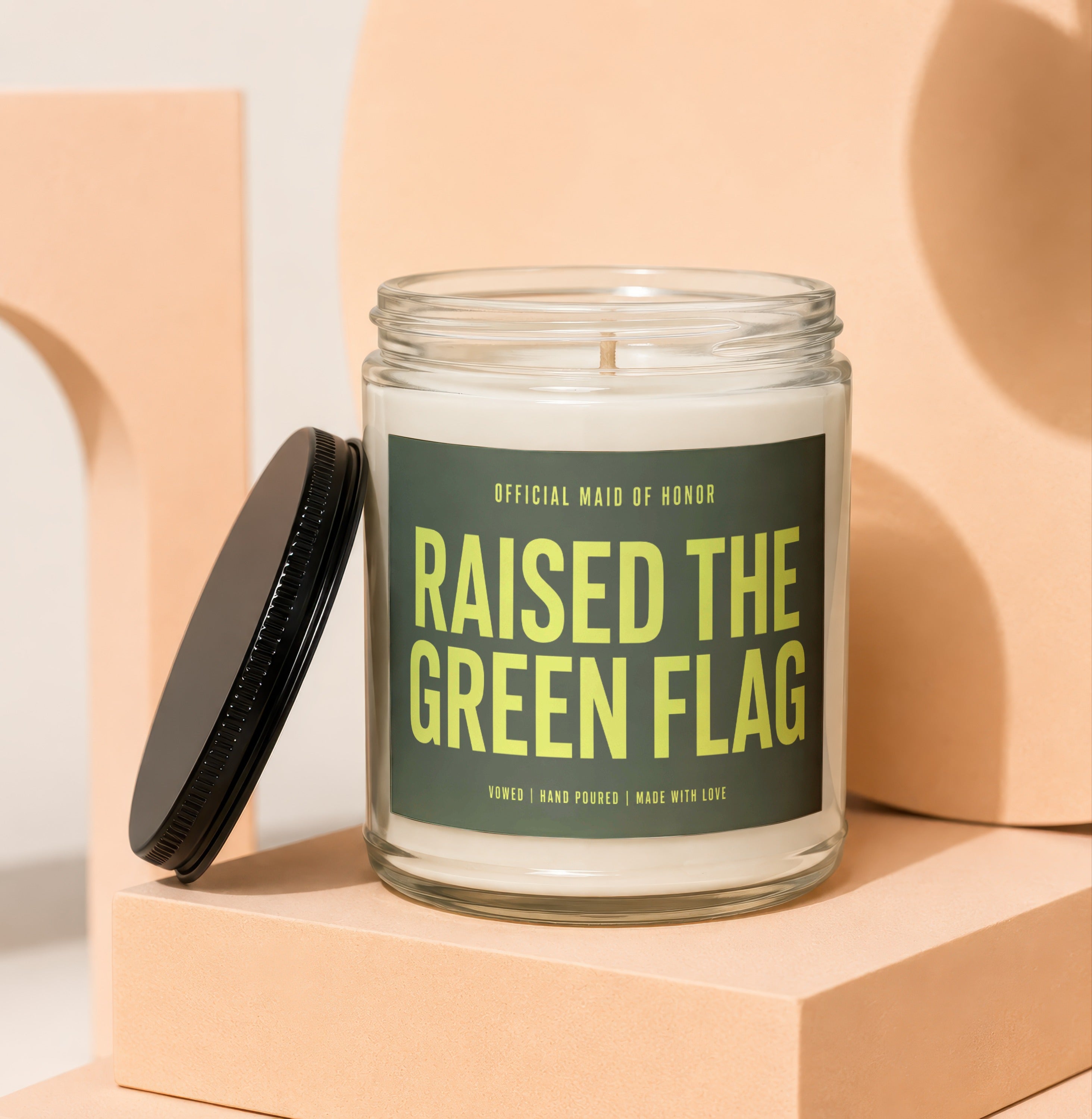 Glass jar candle labeled "RAISED THE GREEN FLAG" for Official Maid of Honor.