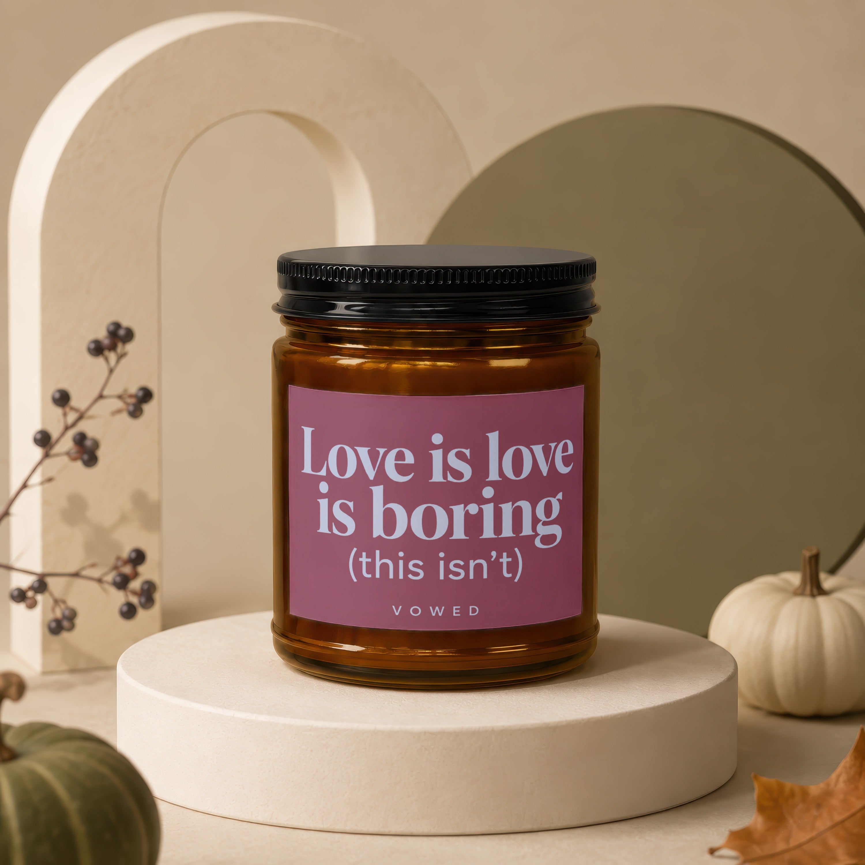 Amber jar candle with pink label text "Love is love is boring (this isn't) VOWED".