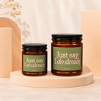 Two amber glass candles with green labels reading "Just say I do already".