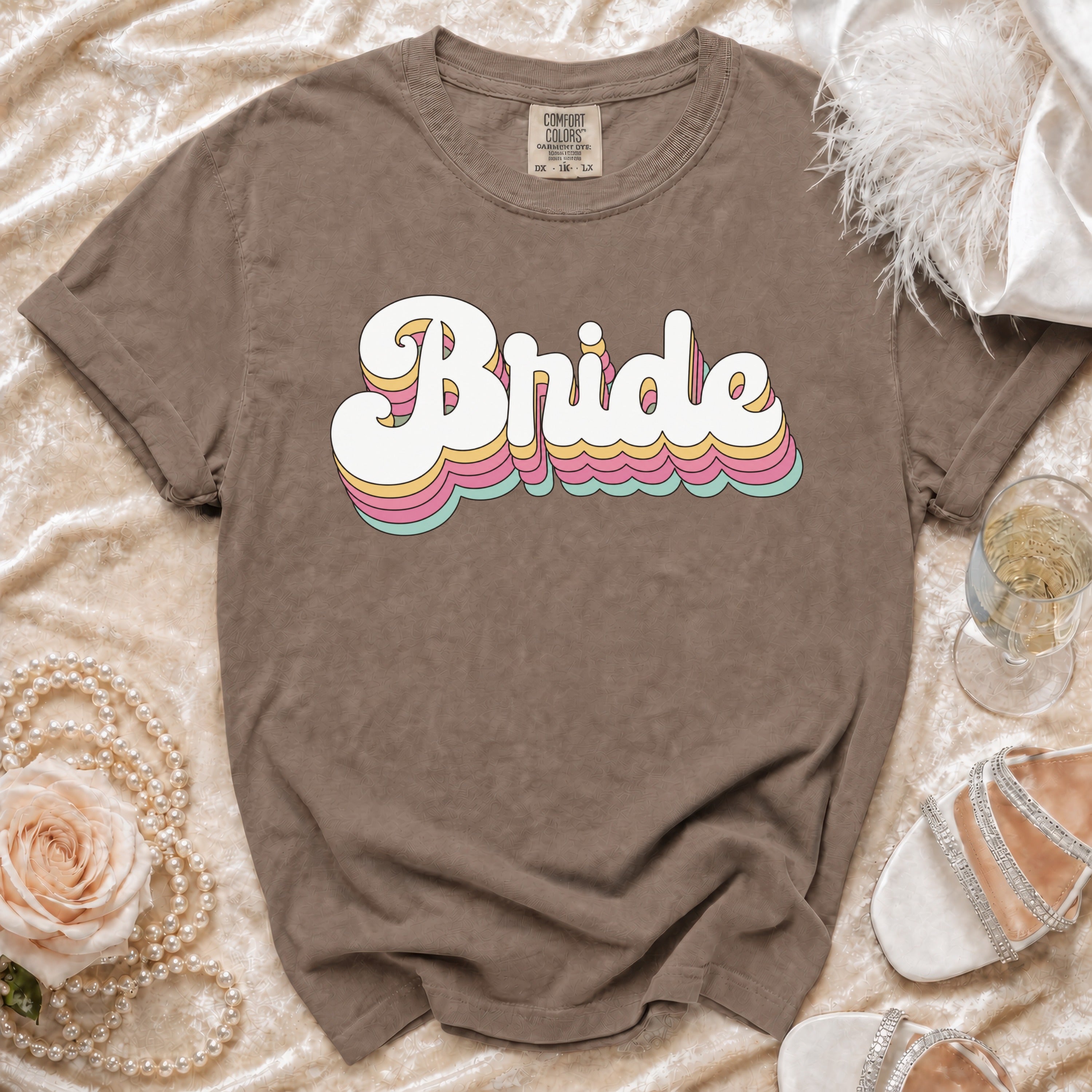 Brown t-shirt with "Bride" in colorful retro text, styled with pearls and heels.