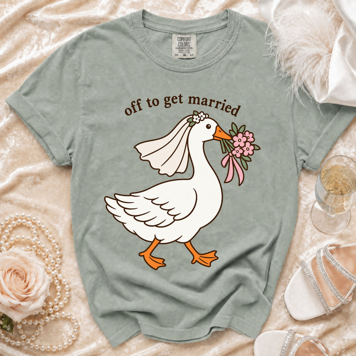 T-shirt with cartoon goose wearing a veil and holding flowers, reads "off to get married".