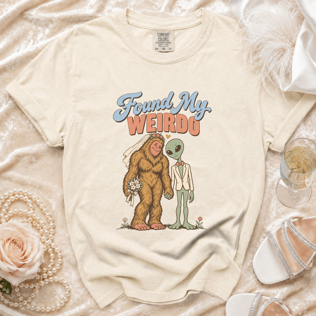T-shirt graphic: Bigfoot and alien couple with text "Found My Weirdo".