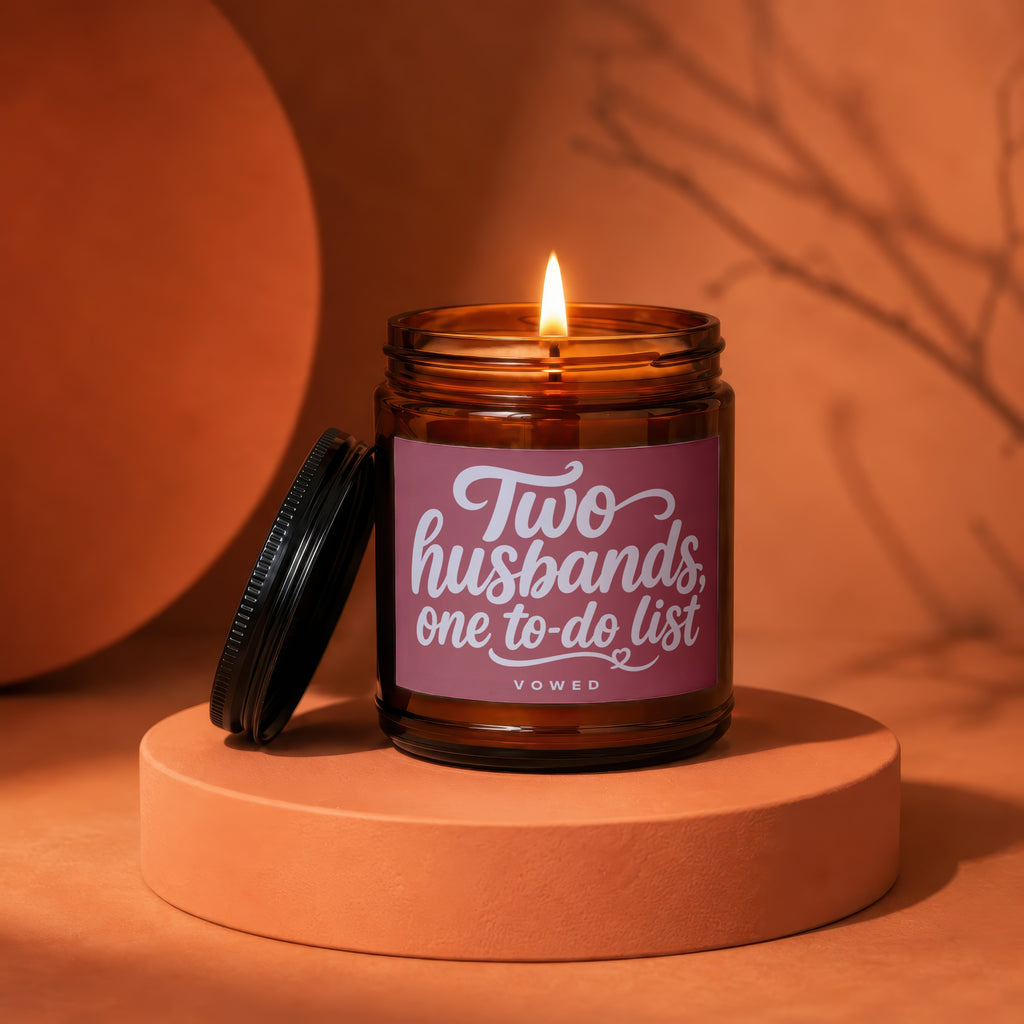 Amber jar candle with open lid, lit wick, and "Two husbands, one to-do list" text.