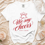 White t-shirt with red graphic text "We say Cheers THE CREW" and champagne glasses.