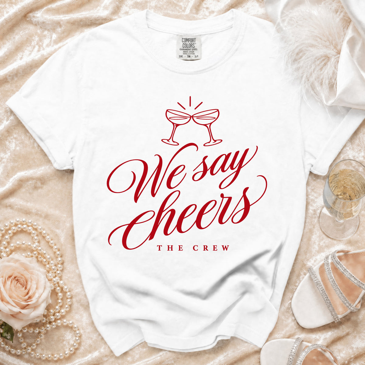 White t-shirt with red graphic text "We say Cheers THE CREW" and champagne glasses.