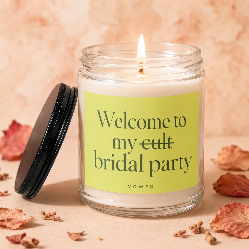 Glass candle with lit wick, reads "Welcome to my cult bridal party"