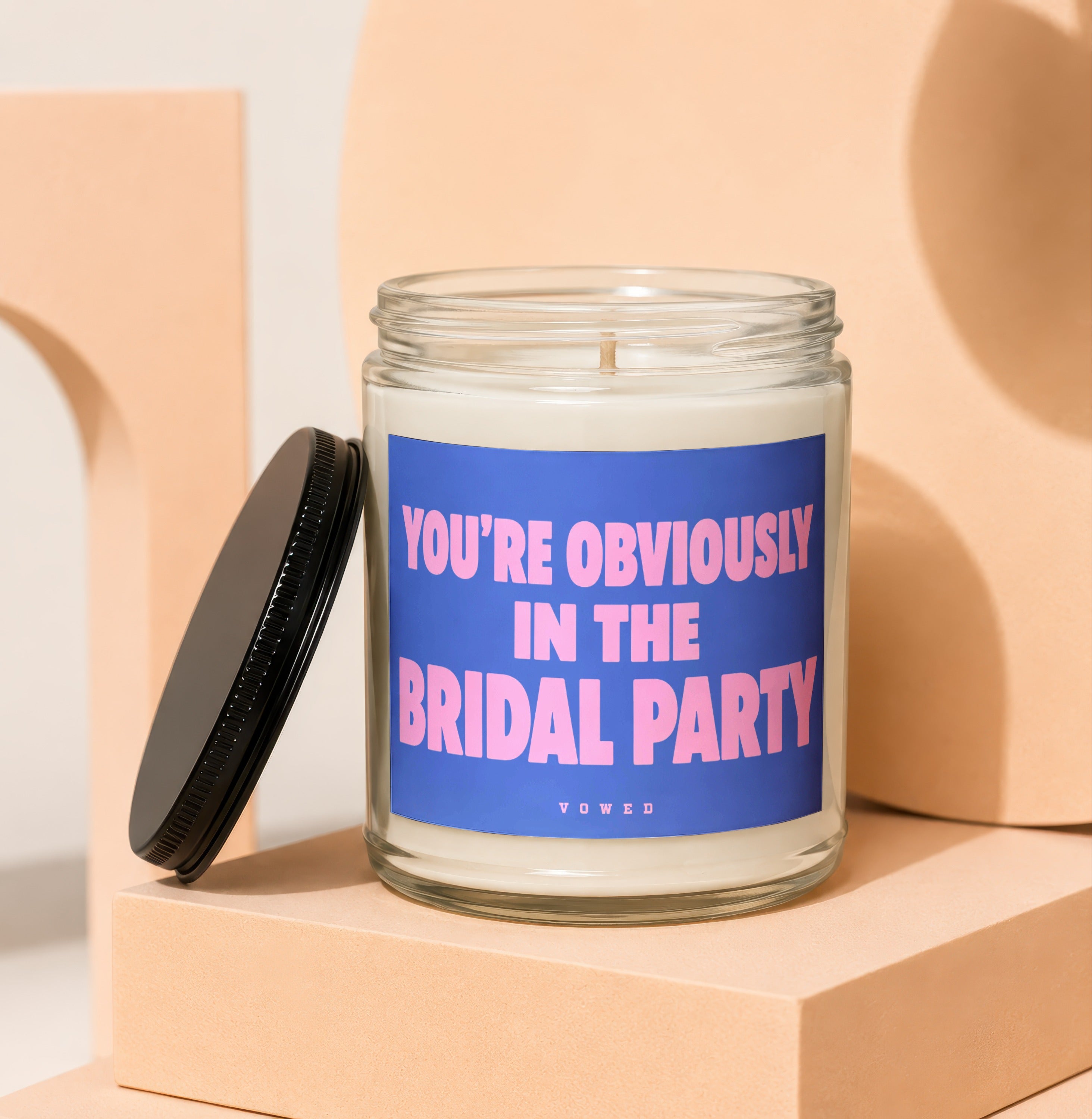 Candle with "YOU'RE OBVIOUSLY IN THE BRIDAL PARTY" text on a blue label and "VOWED" below.