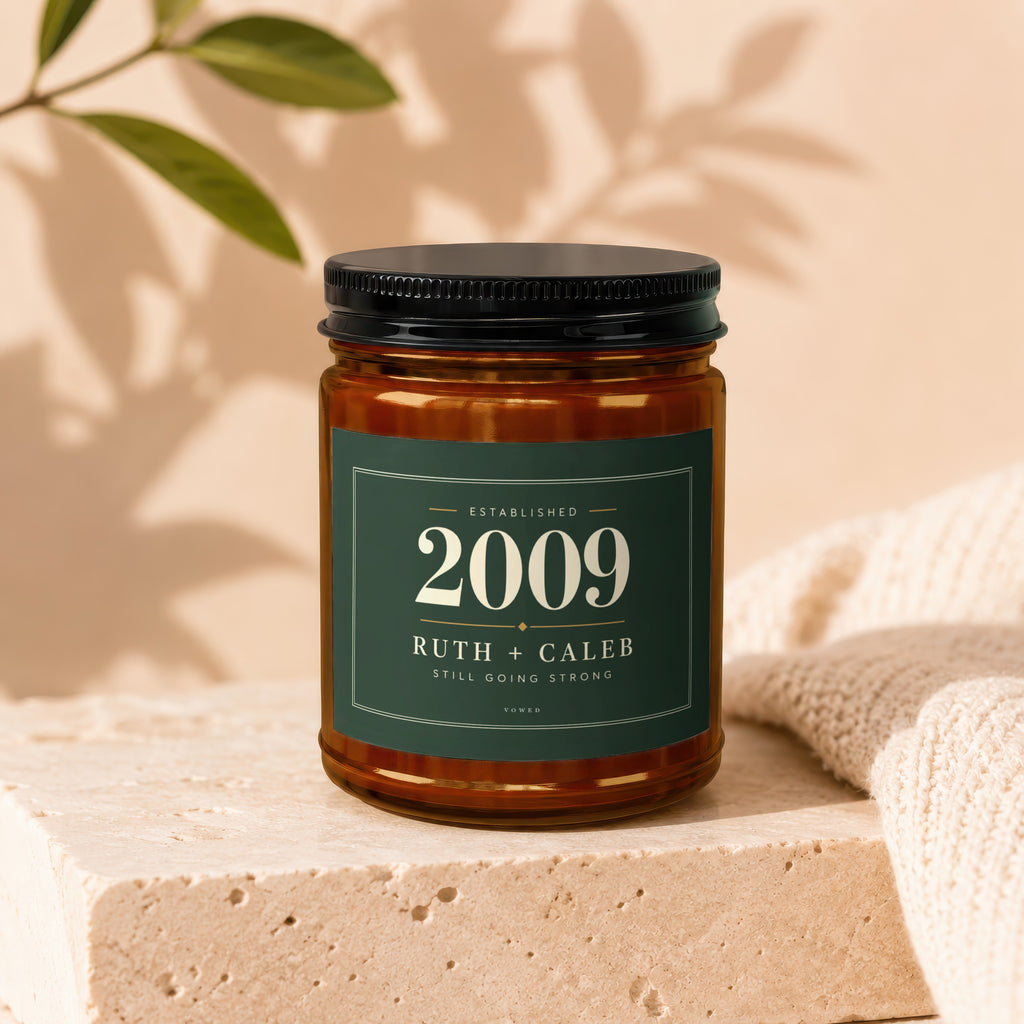 Candle in amber jar with dark green label: "Established 2009 Ruth + Caleb Still Going Strong."