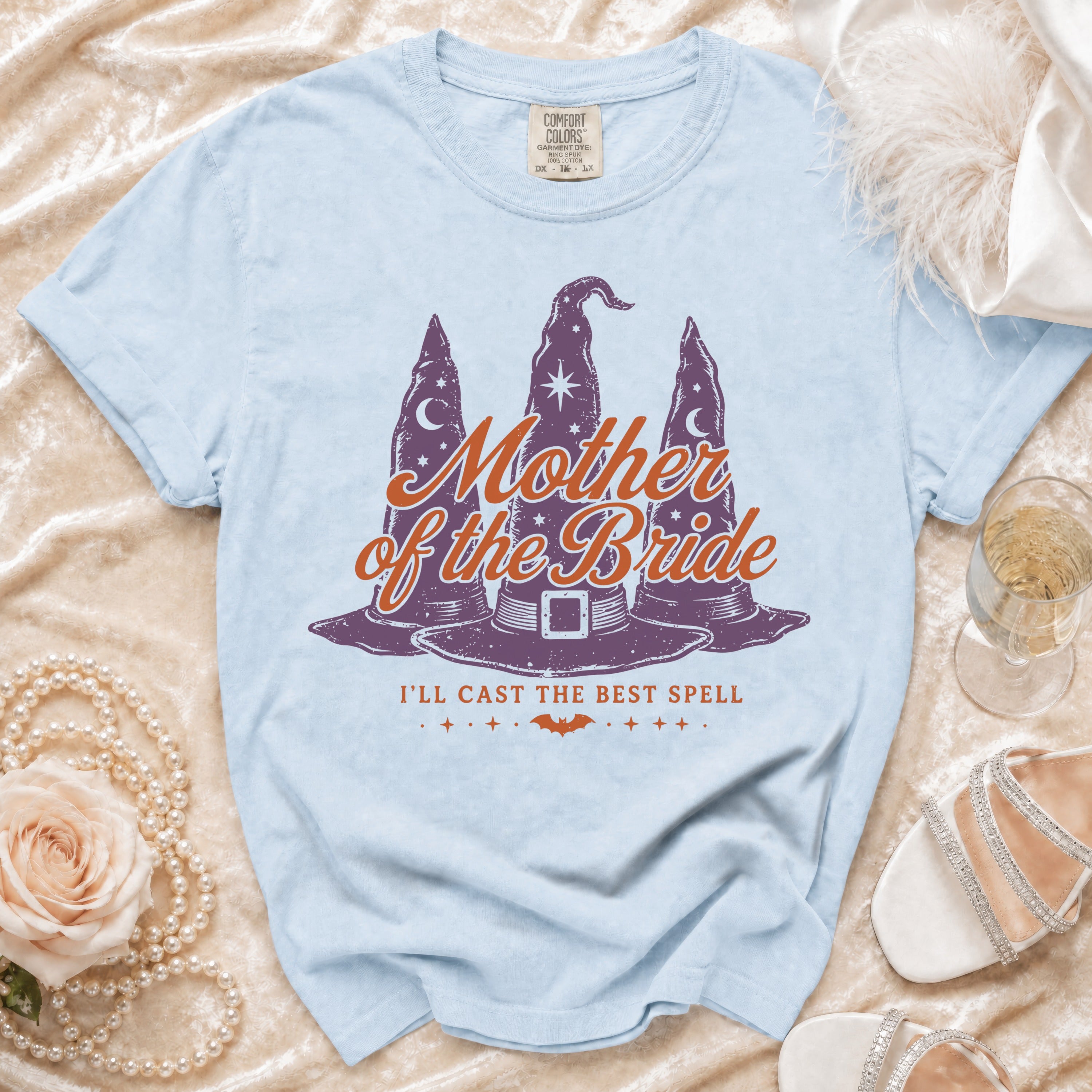 Light blue t-shirt with "Mother of the Bride I'll Cast the Best Spell" graphic.