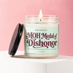 Candle with "MOH Medal of Dishonor" label against pink background.