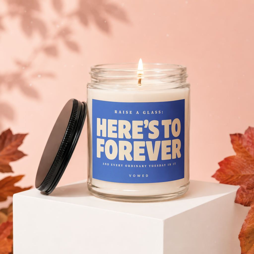 Scented candle with label "RAISE A GLASS: HERE'S TO FOREVER" and other text.