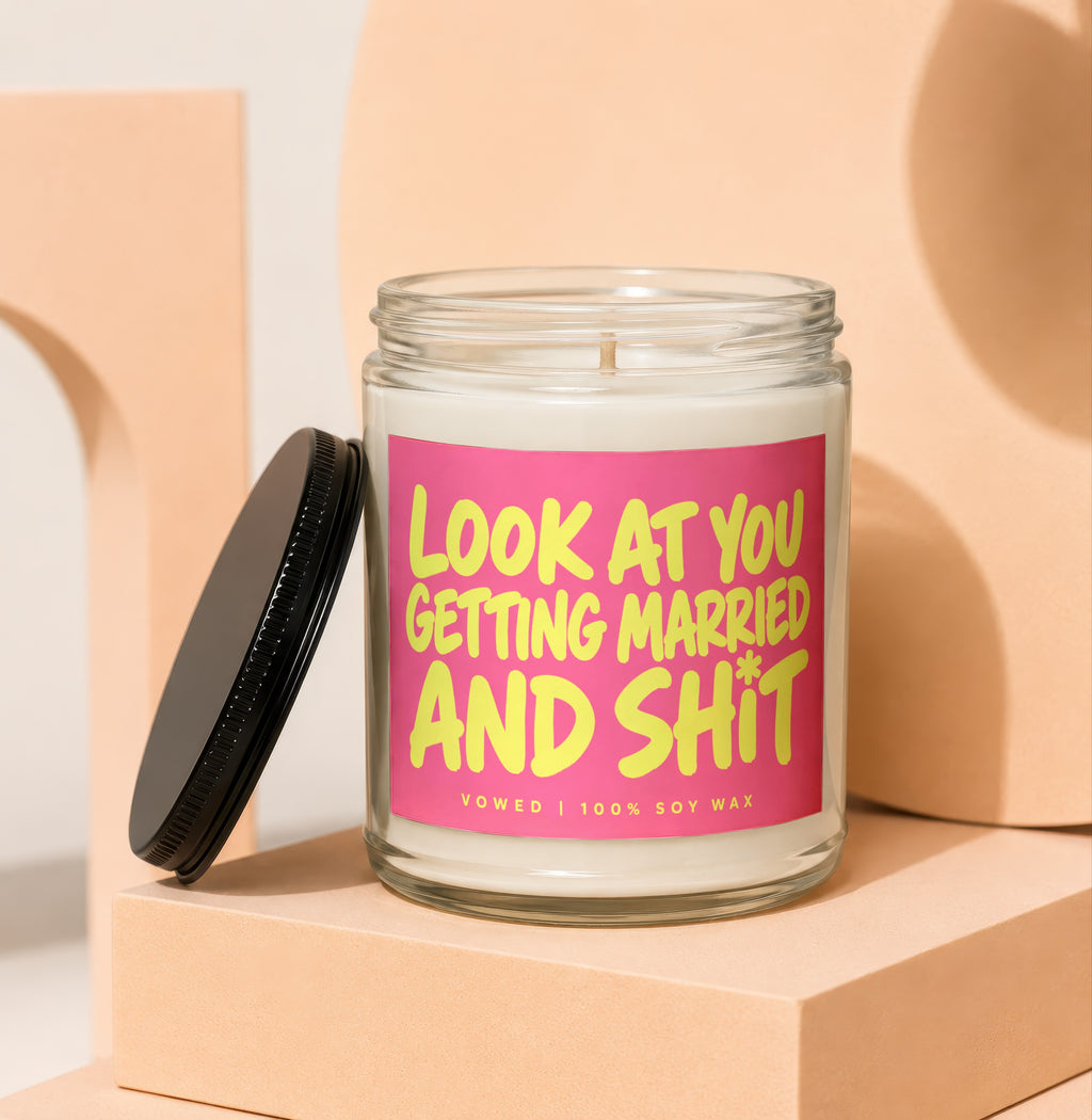 Glass candle with pink label saying "LOOK AT YOU GETTING MARRIED AND SHIT"