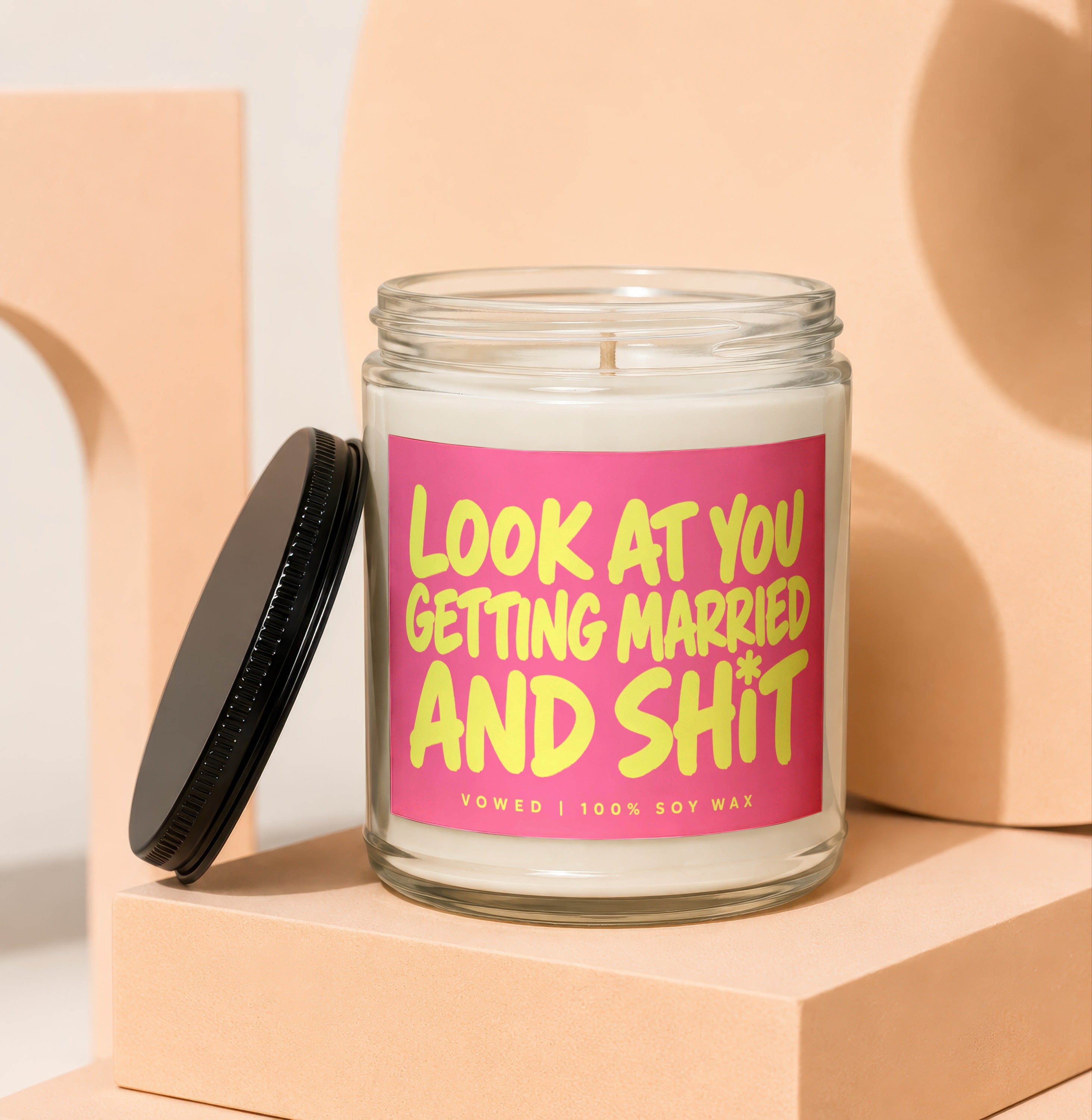 Glass candle with pink label saying "LOOK AT YOU GETTING MARRIED AND SHIT"