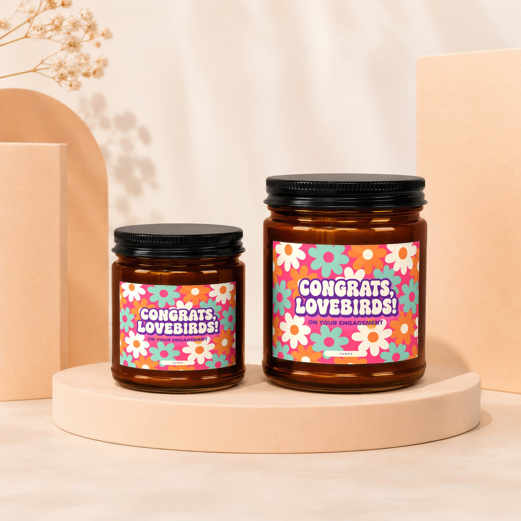 Two amber glass candles with "Congrats, Lovebirds! On Your Engagement" text on floral labels.