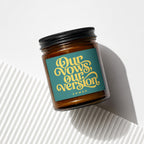 Amber candle in glass jar with teal label reading "Our vows, our version" and "VOWED".