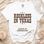 White t-shirt with "Reckless in Texas Olivia's Bach" text for Austin, TX Summer 2026.
