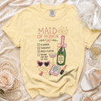 Yellow t-shirt with "Maid of Honor" graphic, checklist, champagne, and accessories.