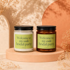 Two candles with black lids and green labels reading "Welcome to my cult bridal party".