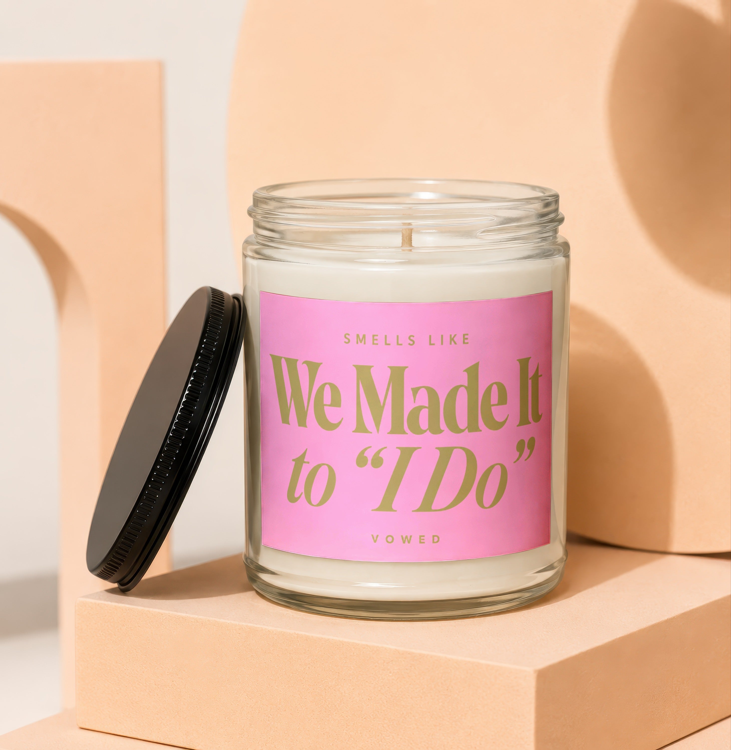 Glass candle with pink label that reads "Smells Like We Made It to 'I Do'".