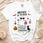 White t-shirt with "Mother of the Bride Raising Hell & Raising Standards" graphic.