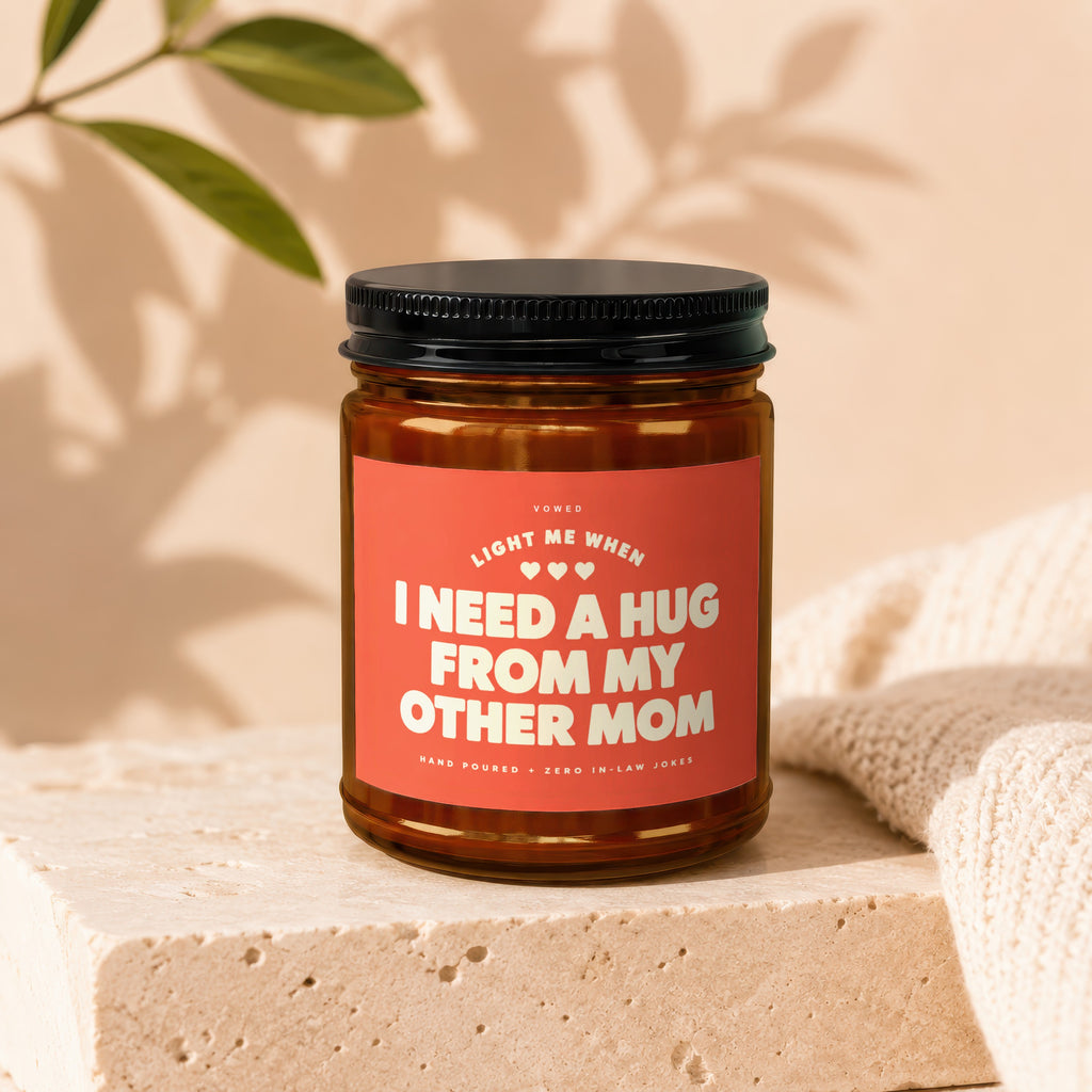 Candle with text "I Need A Hug From My Other Mom" on coral label.