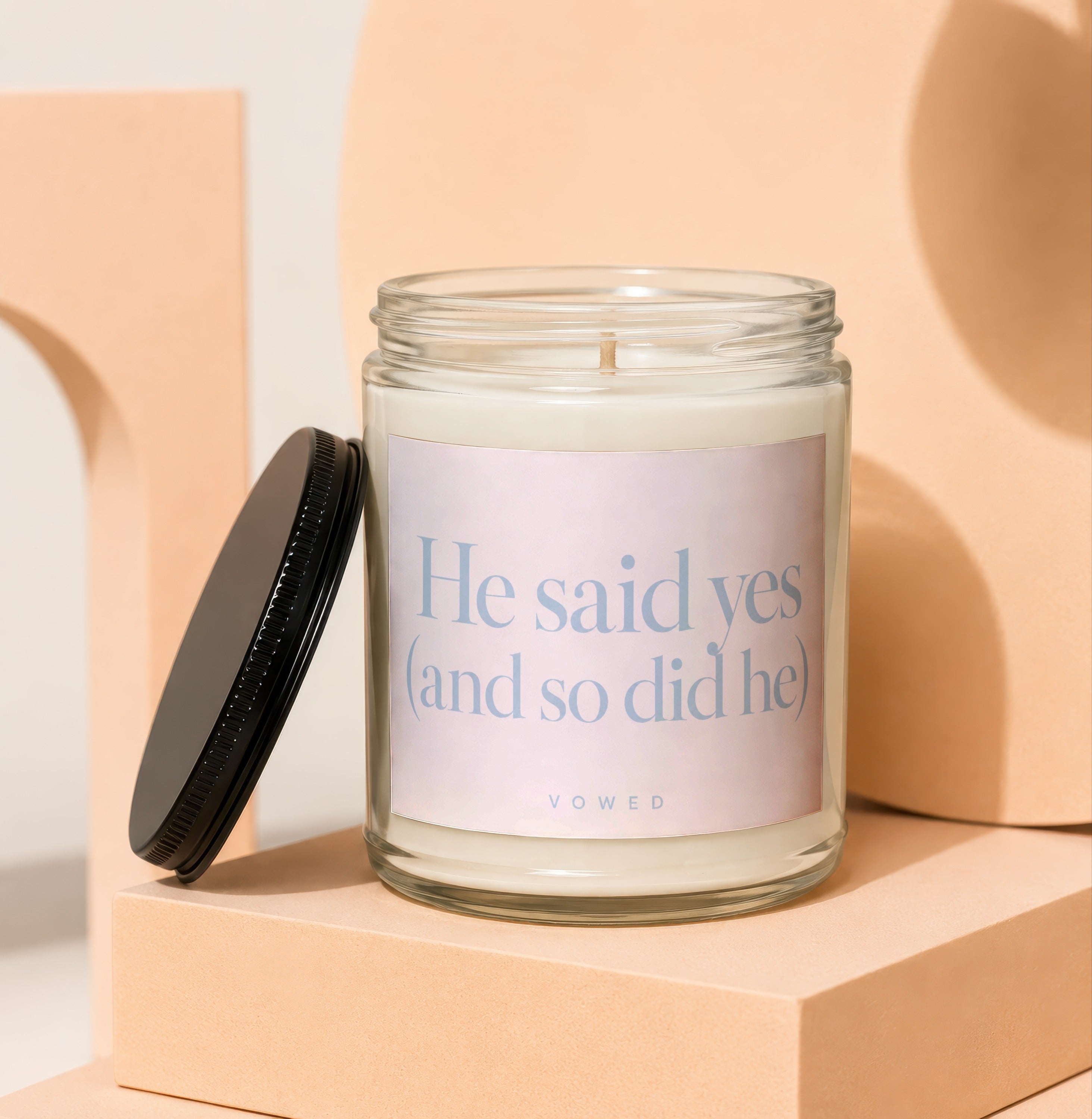 Glass candle with black lid and label reading "He said yes (and so did he) VOWED".