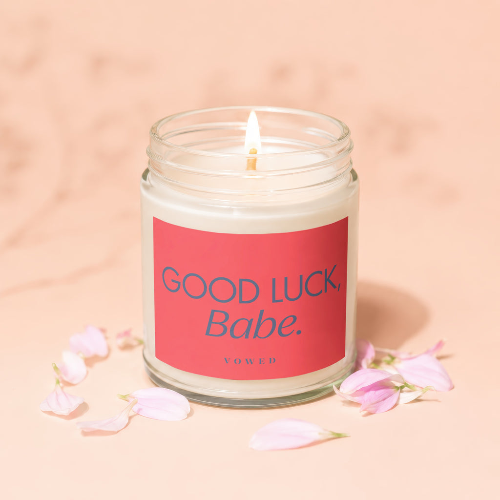 Jar candle with "Good Luck, Babe." text on a pink label, surrounded by petals.