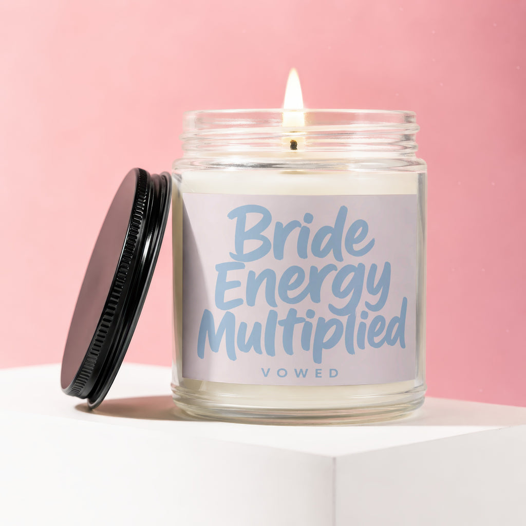 Lit candle in glass jar with black lid, labeled "Bride Energy Multiplied VOWED".
