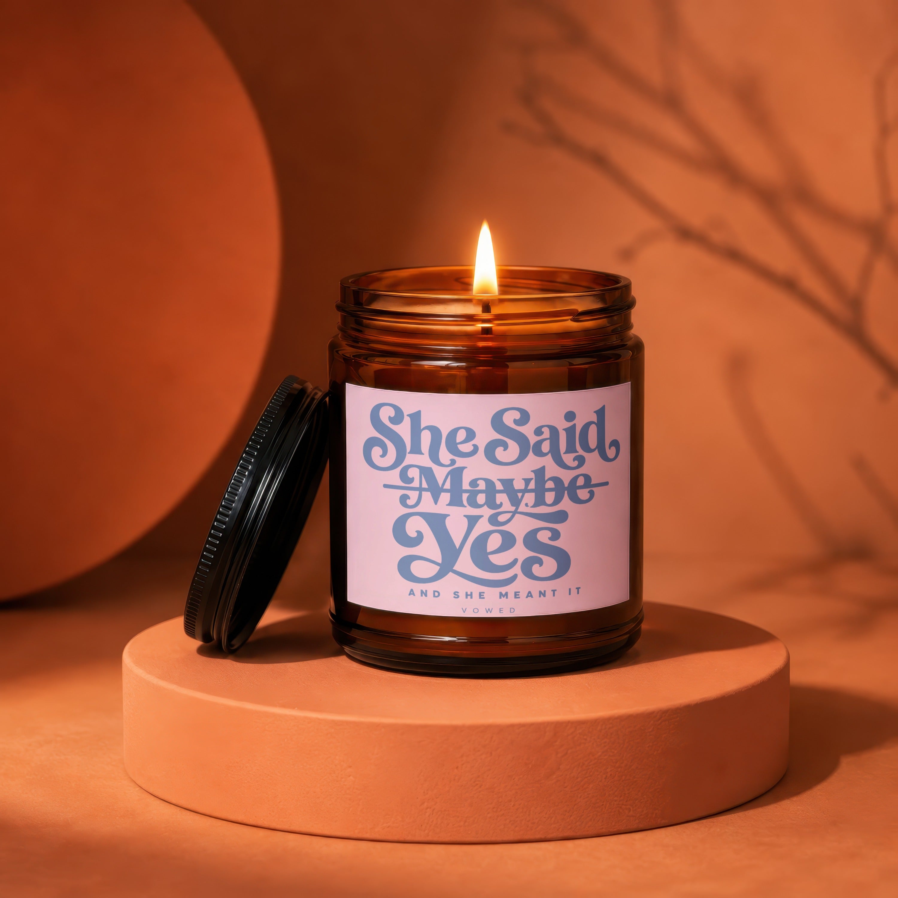 Amber jar candle with pink label that says "She Said Maybe Yes"