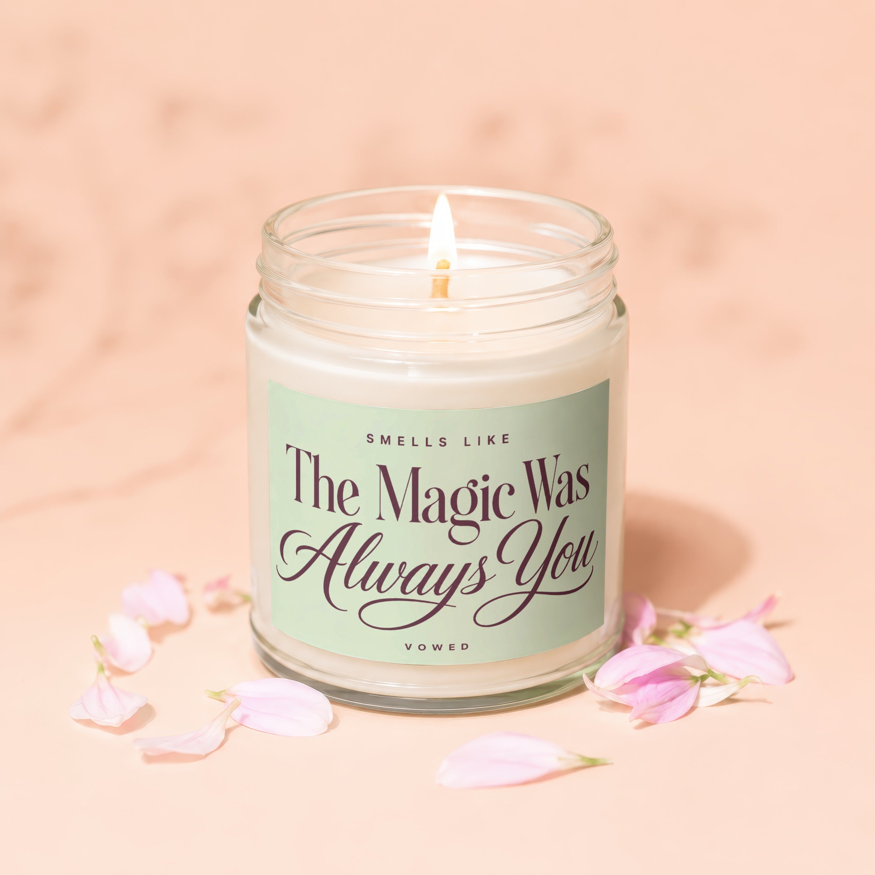Lit candle with "The Magic Was Always You" text, surrounded by pink petals.