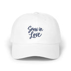 A white baseball cap with the blue embroidered text Snow in Love on the front.