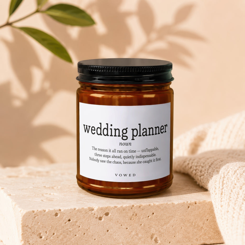 Amber jar candle with "wedding planner" definition label and "VOWED" text.