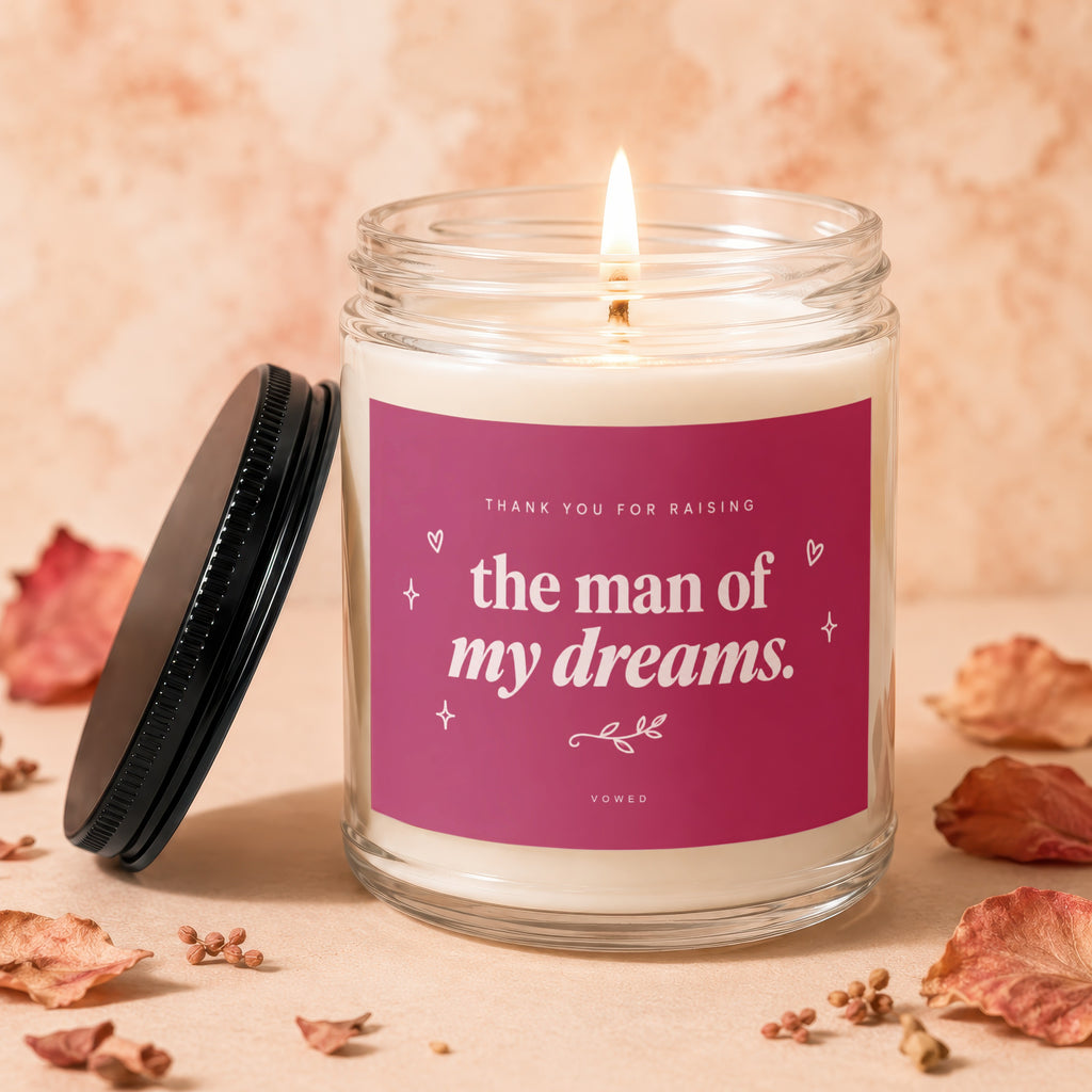 Glass candle with lit wick and label reading "the man of my dreams."