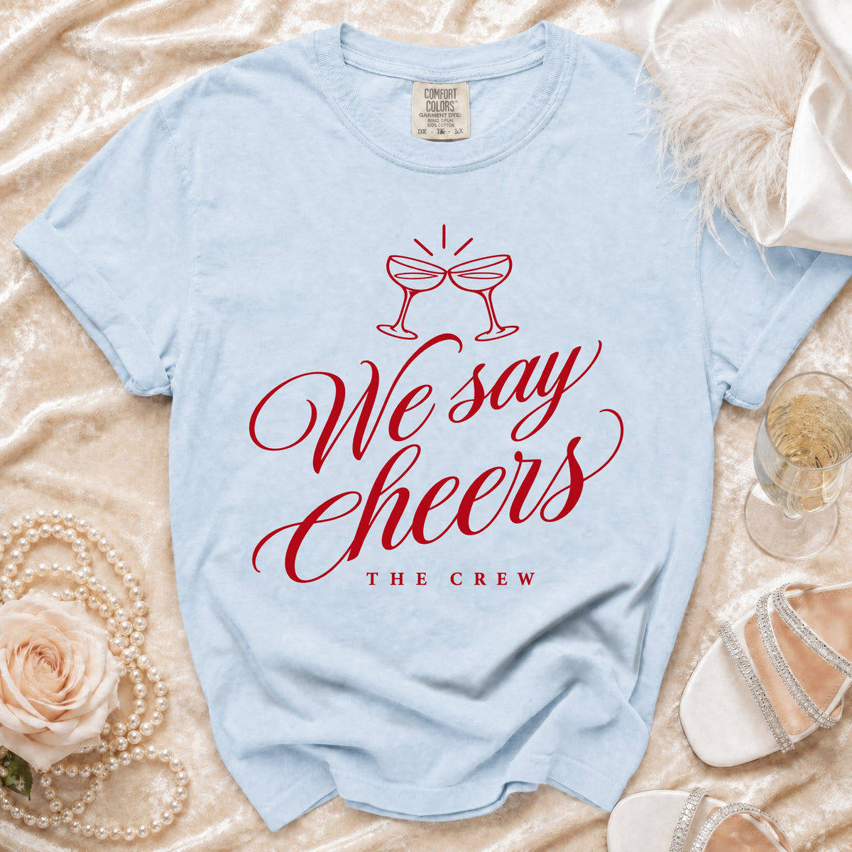 Light blue t-shirt with red text "We say Cheers THE CREW" and wine glasses.