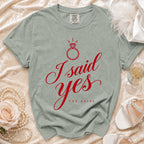 Sage green crewneck t-shirt featuring red script text reading I said yes above The Bride.