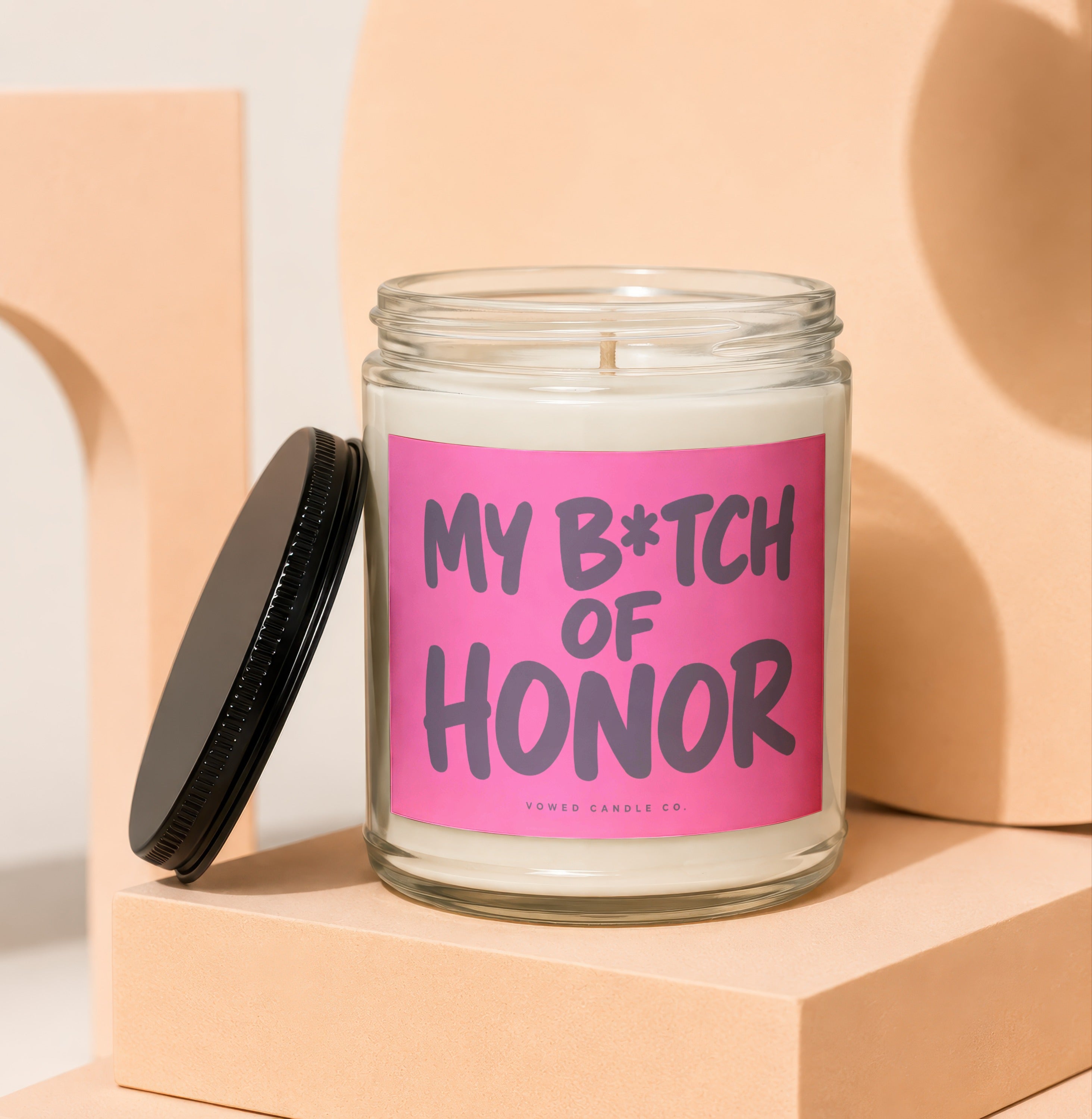 Glass candle with pink label reading "My B*tch of Honor" by Vowed Candle Co.