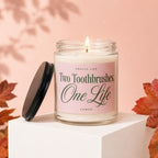 Lit candle in glass jar labeled "Two Toothbrushes, One Life Vowed"