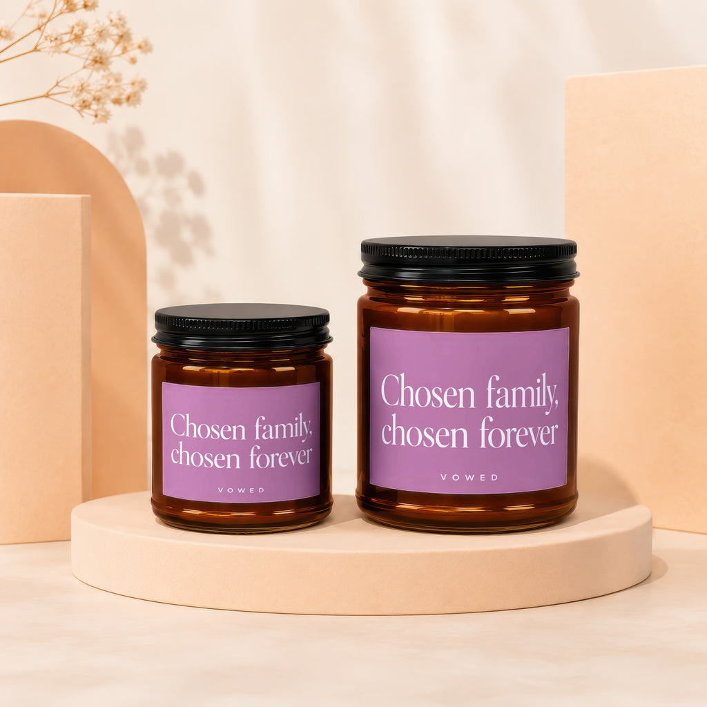 Two candles with black lids on display stands, labeled "Chosen family, chosen forever".