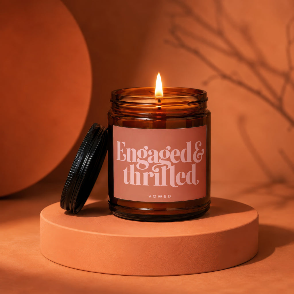 Amber glass candle with lit flame and "Engaged & thrilled vowed" label.