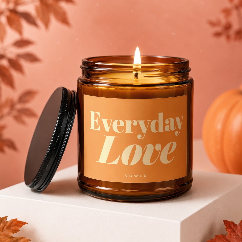 Lit amber candle with "Everyday Love" text, lid off, autumn theme.