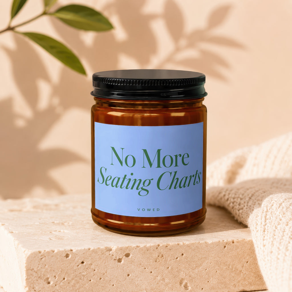 Amber candle in glass jar with black lid, blue label reads "No More Seating Charts Vowed".