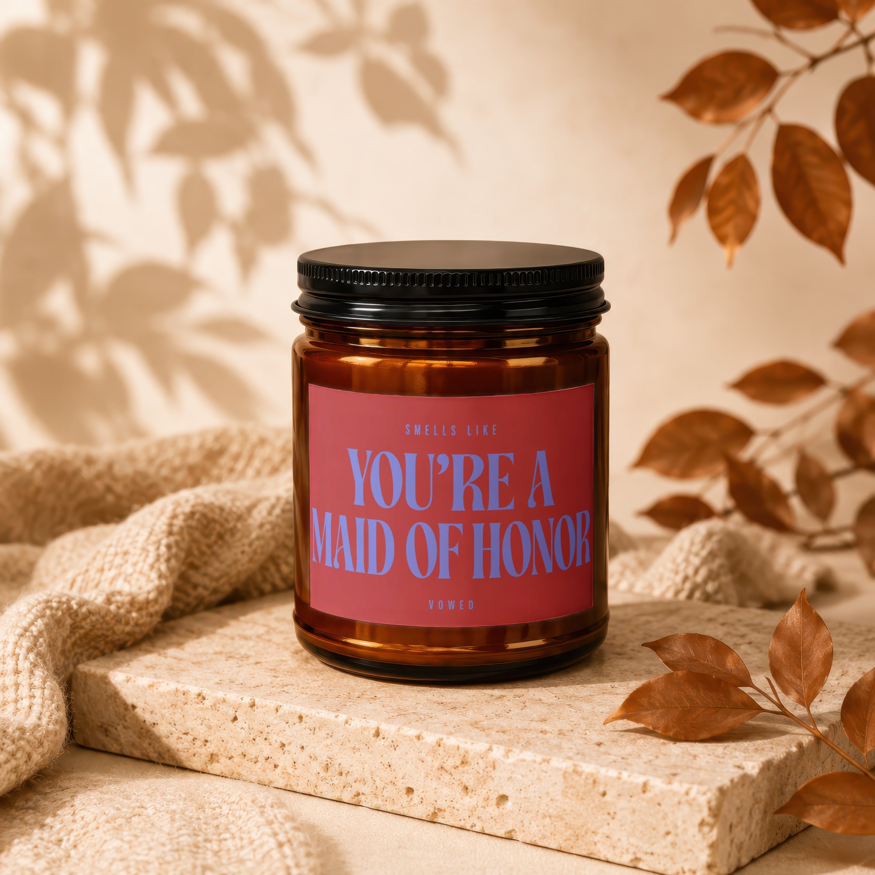 Brown glass candle with pink label reading "YOU'RE A MAID OF HONOR".