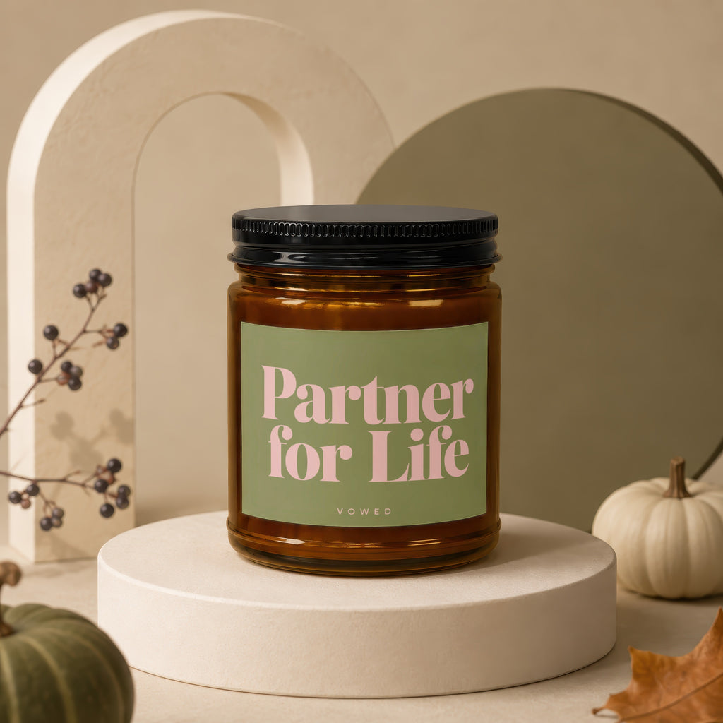 Amber candle with "Partner for Life" text on green label, on pedestal.