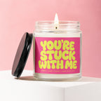 Glass candle with lit wick and label reading "YOU'RE STUCK WITH ME"