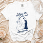 White t-shirt with navy graphic saying "Holding her dress and her secrets".