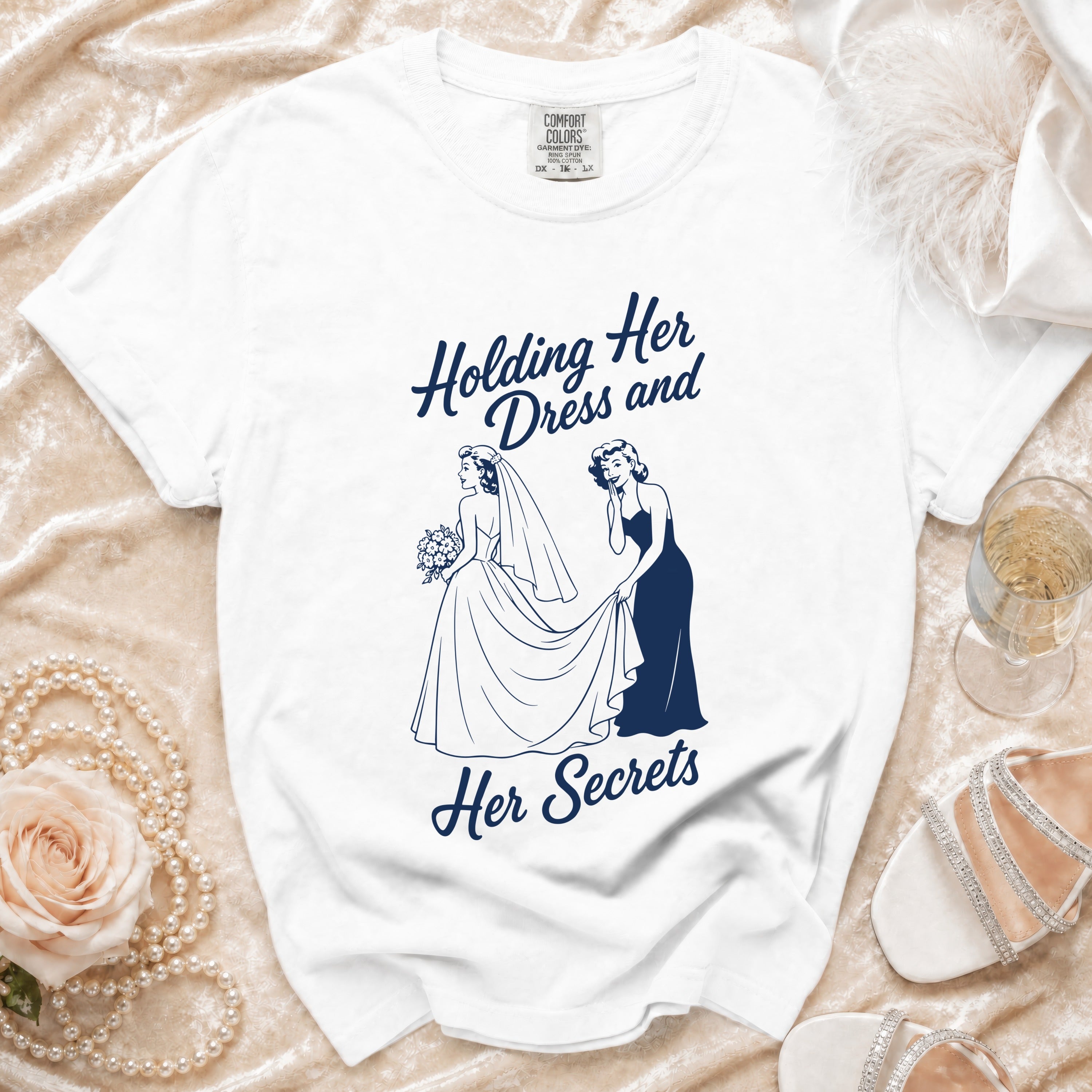 White t-shirt with navy graphic saying "Holding her dress and her secrets".