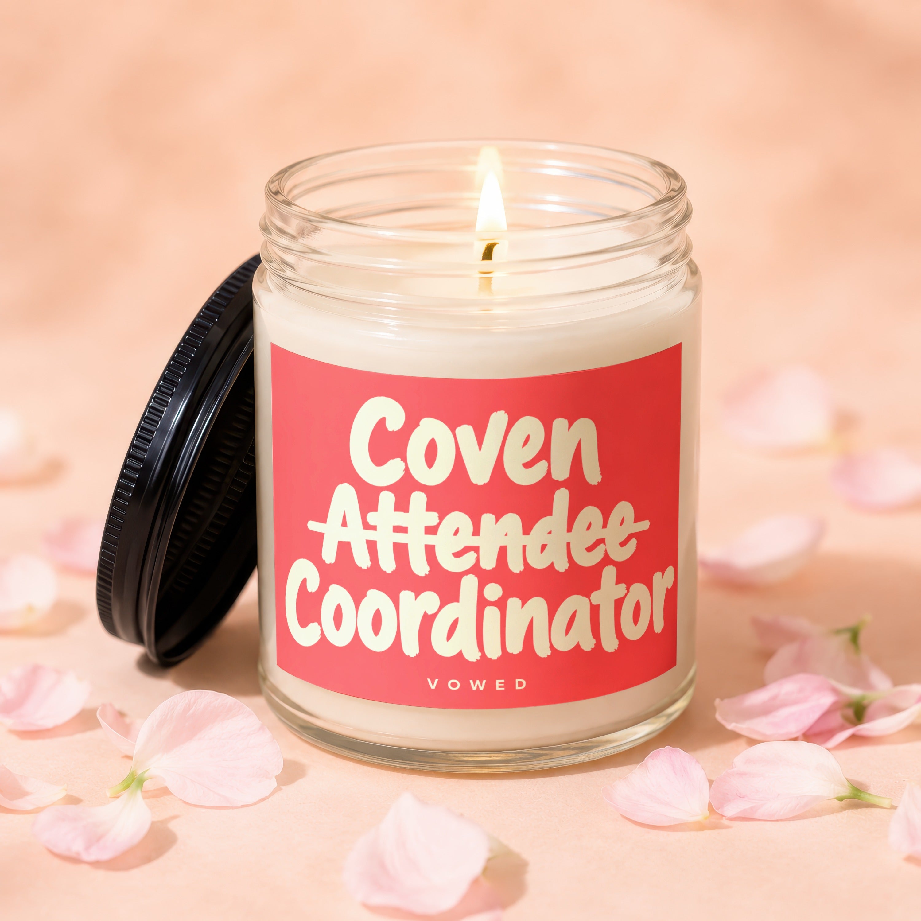 Candle with lit wick and lid off reading "Coven Attendee Coordinator VOWED".