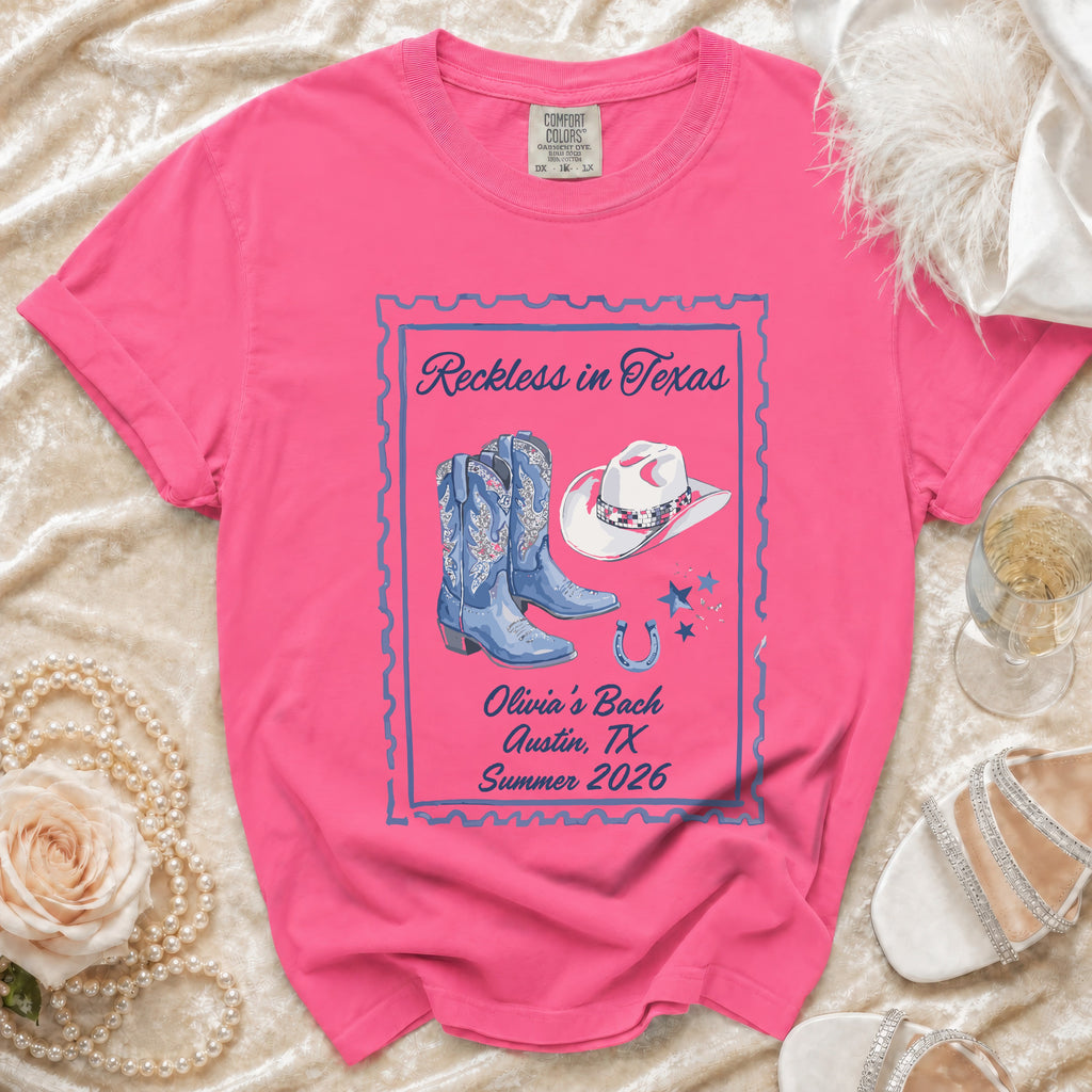 Pink t-shirt with "Reckless in Texas" and cowboy boots graphic.
