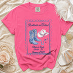 Pink t-shirt with "Reckless in Texas" and cowboy boots graphic.