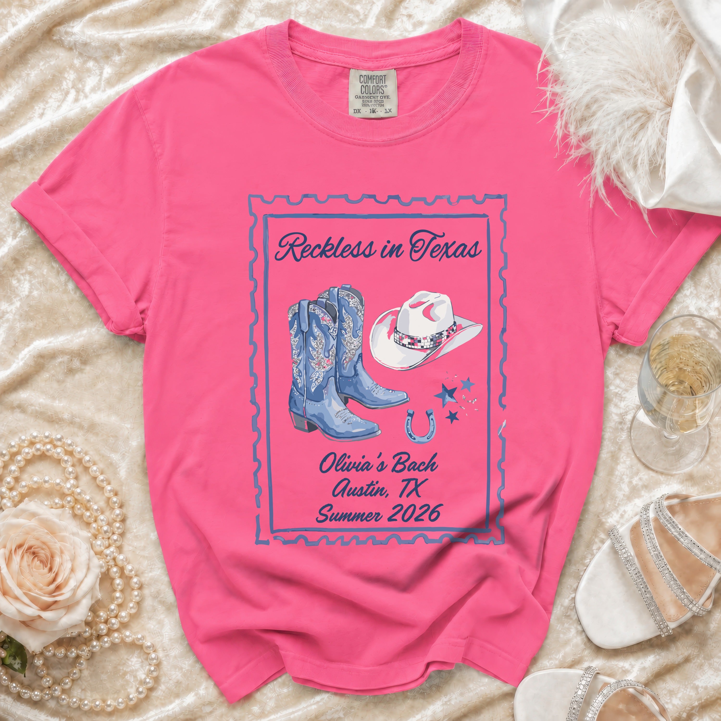 Pink t-shirt with "Reckless in Texas" and cowboy boots graphic.